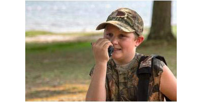  A boy speaking to a radio, held close to his mouth in his right hand   